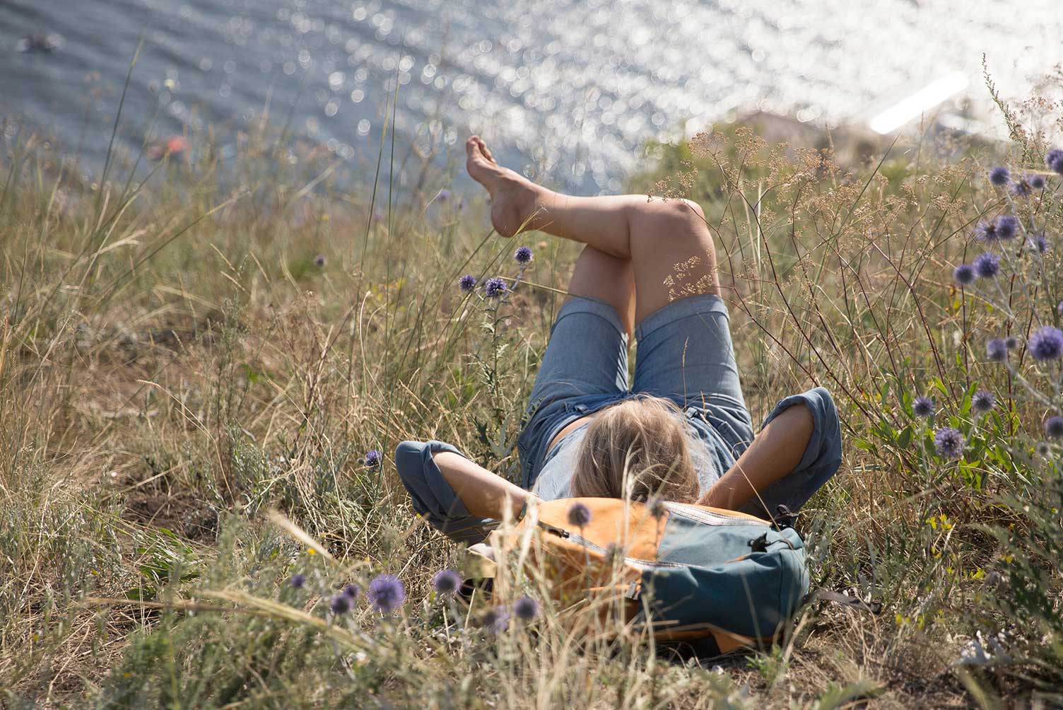 Mujer viajera tumbada relajándose a la orilla de un río