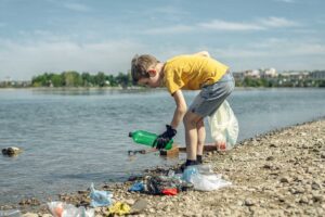 Niño recogiendo basura cerca de un lago