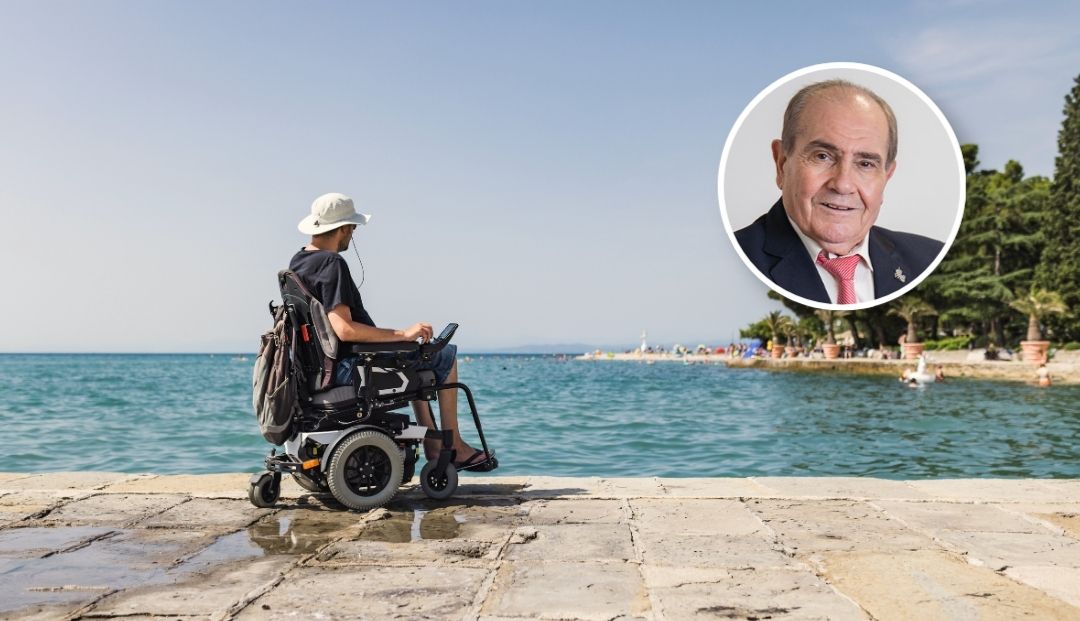Vista de una persona en silla de ruedas en una playa con una foto de Juan Caballero, presidente de honor de ATF Turisferr en la esquina